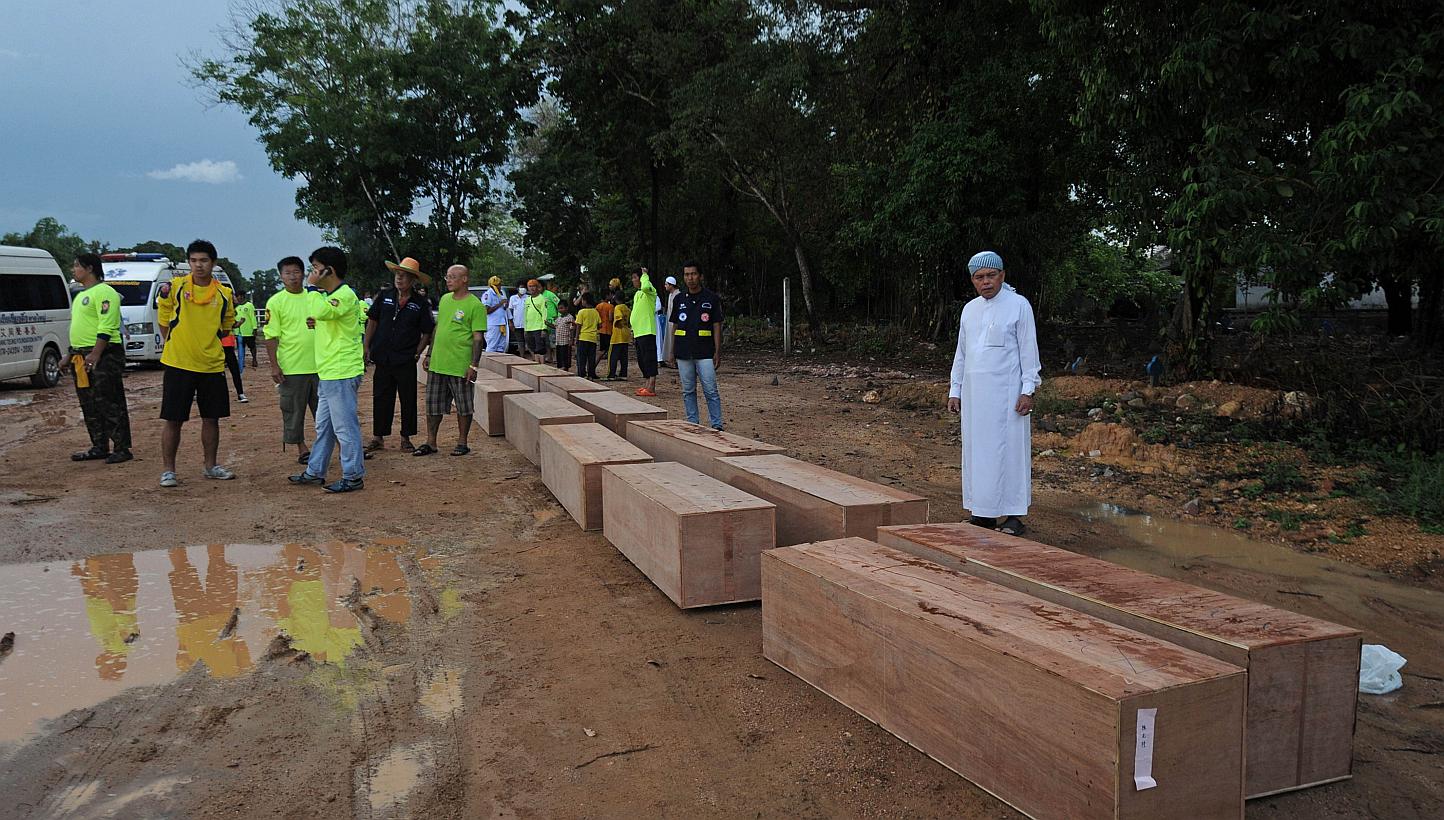 Rescue workers bring coffins containing the human remains of migrants exhumed the day before from a mass grave at an abandoned jungle camp in the Sadao district of Thailand's southern Songkhla province bordering Malaysia, for burial at a cemetery out