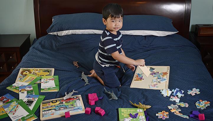Elijah Catalig, at an age of two years and six months, is currently the youngest member in Mensa Singapore. He is pictured at home with some of his puzzles, games and activity books on May 7, 2015. -- ST PHOTO: MARK CHEONG