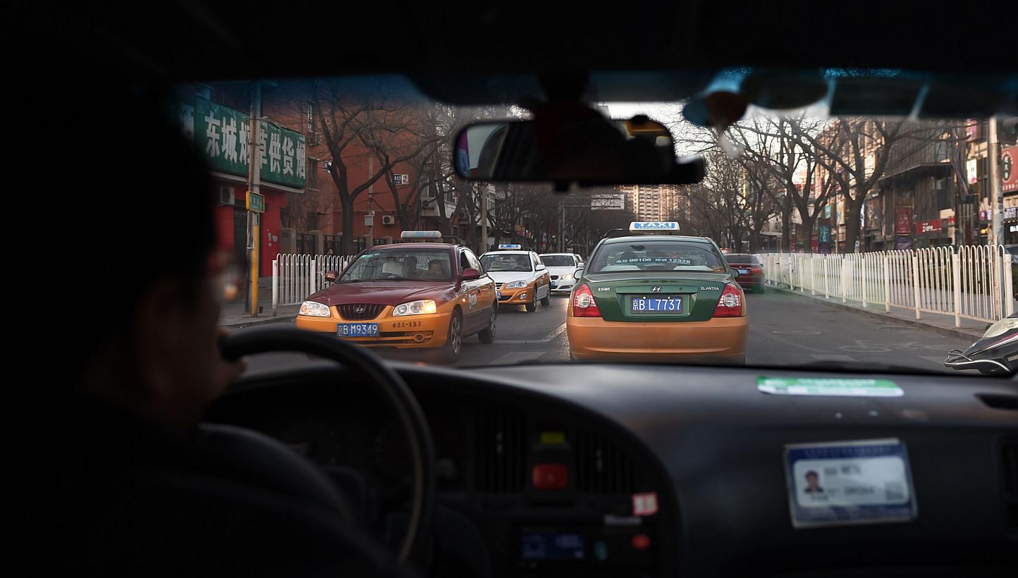 A Feb 16, 2015 photo shows a taxi driver following another taxi on a street in Beijing. China's crackdown on ride-sharing app Uber may have less to do with protecting the owners of politically powerful taxi services than placating the taxi industry's