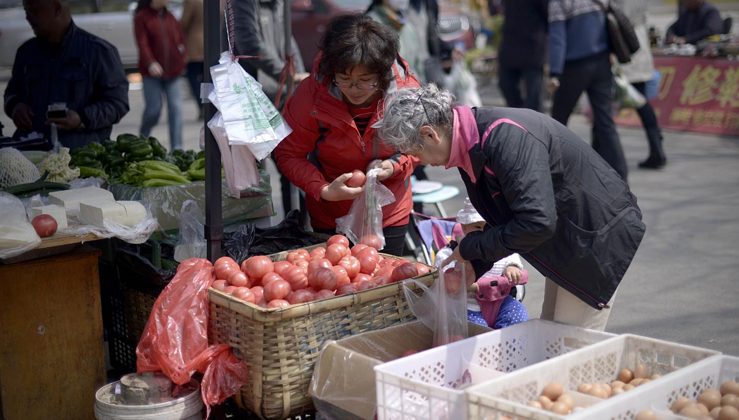 People buying vegetables at an outdoor market in Beijing on April 10, 2015. -- PHOTO: AFP