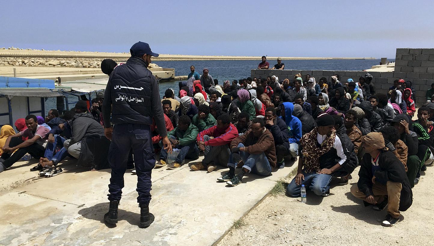 A coast guard (back to camera) stands over illegal migrants who attempted to sail to Europe, on the shore after the migrants' boat was intercepted at sea by the Libyan coast guard, at Khoms, Libya on&nbsp;May 6, 2015. Defence ministers from five Euro