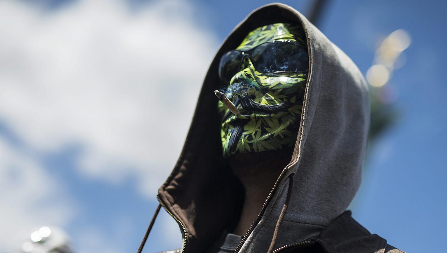 A protestor, wearing an anonymous mask with hemp leaves painted on it, smokes cannabis during a demonstration for the legalisation and re-classification of the substance at Place de la Bastille in Paris, France, on May 9, 2015. -- PHOTO: EPA&nbsp;
