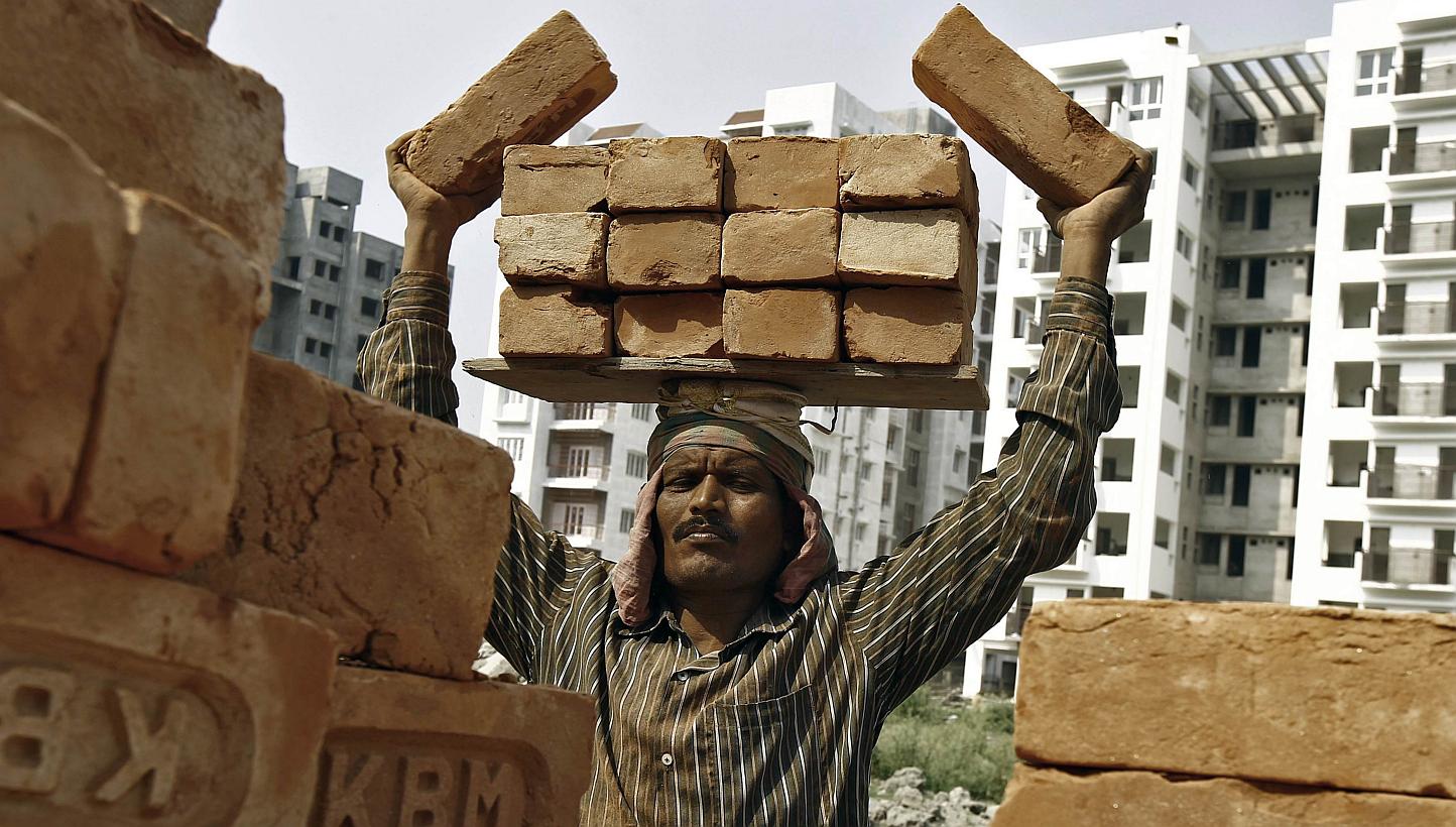 A labourer stacks bricks on his head at the construction site of a residential complex in Kolkata Feb 28, 2015.&nbsp;India's economy grew an estimated 7-7.5 per cent last fiscal year and will keep growing this year, but the government will have to in