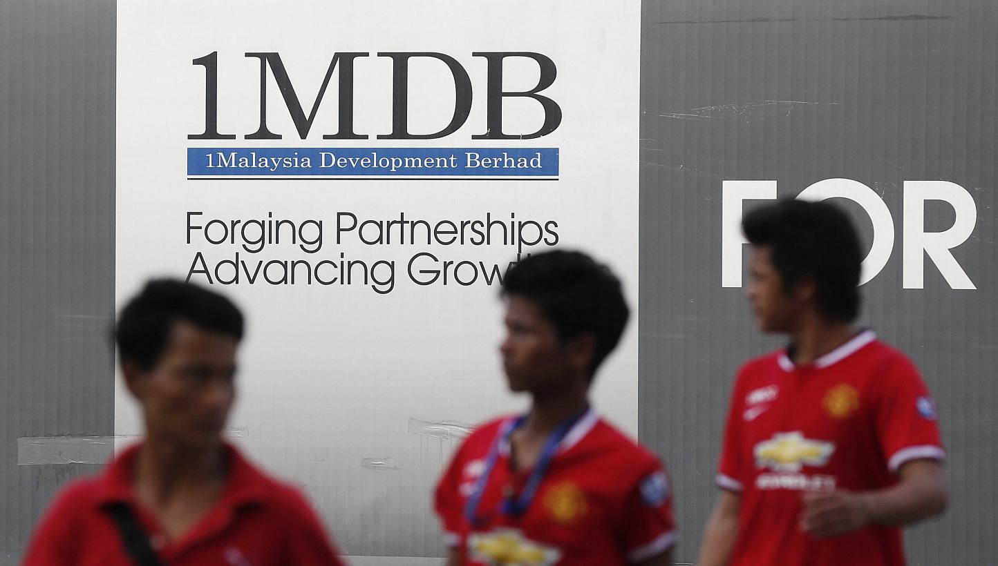 Men walking past a 1 Malaysia Development Berhad (1MDB) billboard at the funds flagship Tun Razak Exchange development in Kuala Lumpur on March 1, 2015. -- PHOTO: REUTERS