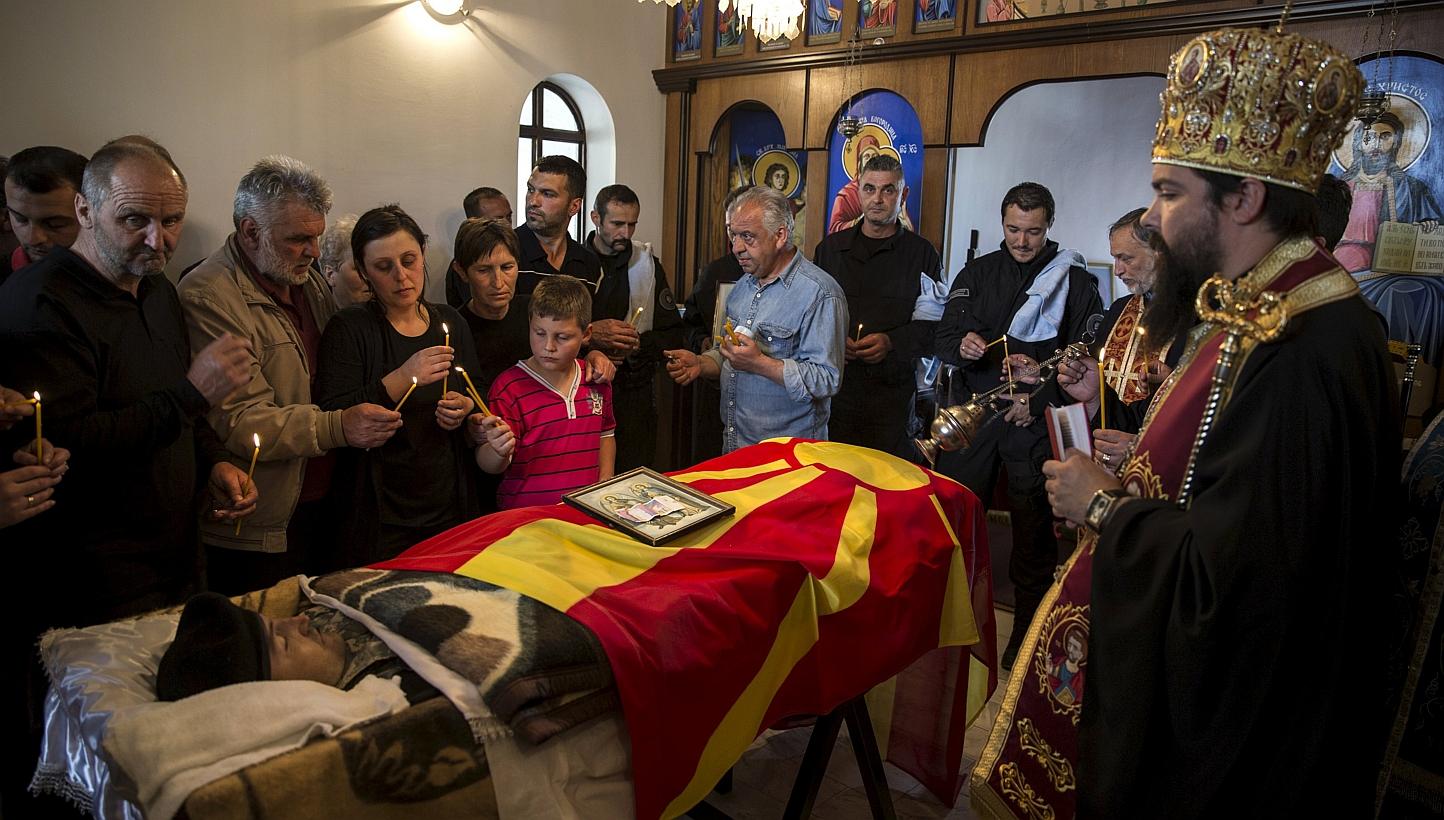 Relatives of &nbsp;policeman Zarko Kuzmanovski mourn next to his coffin draped with the Macedonian flag inside a church during his funeral in the village of Brvenica, Macedonia on Sunday. -- PHOTO: REUTERS
