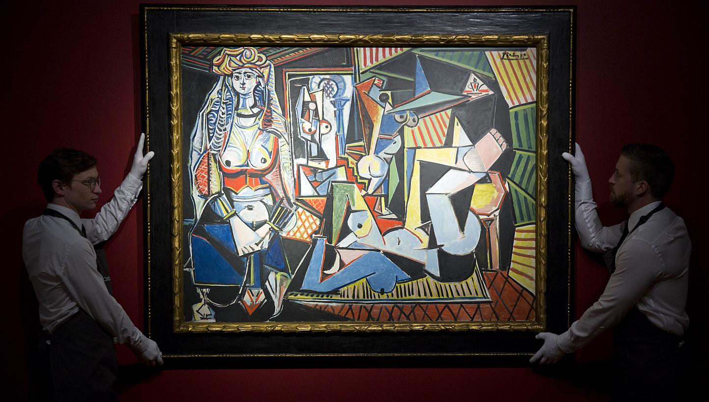 Employees of Christie's auction house holding up Pablo Picasso’s Les femmes d’Alger (Version ‘O’) during a press preview in London on April 10, 2015. -- PHOTO: AFP