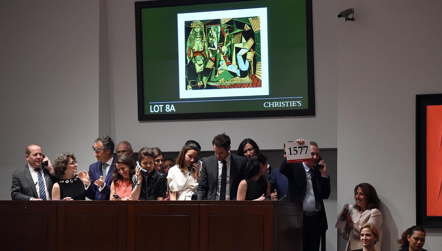 A phone bidder holds up the winning bidder paddle after the Picasso masterpiece "Les Femmes d'Alger (Version O)" sold for USD179.3 million at Christie's in New York City on May 11, 2015, smashing the record for most expensive art sold at auction. --