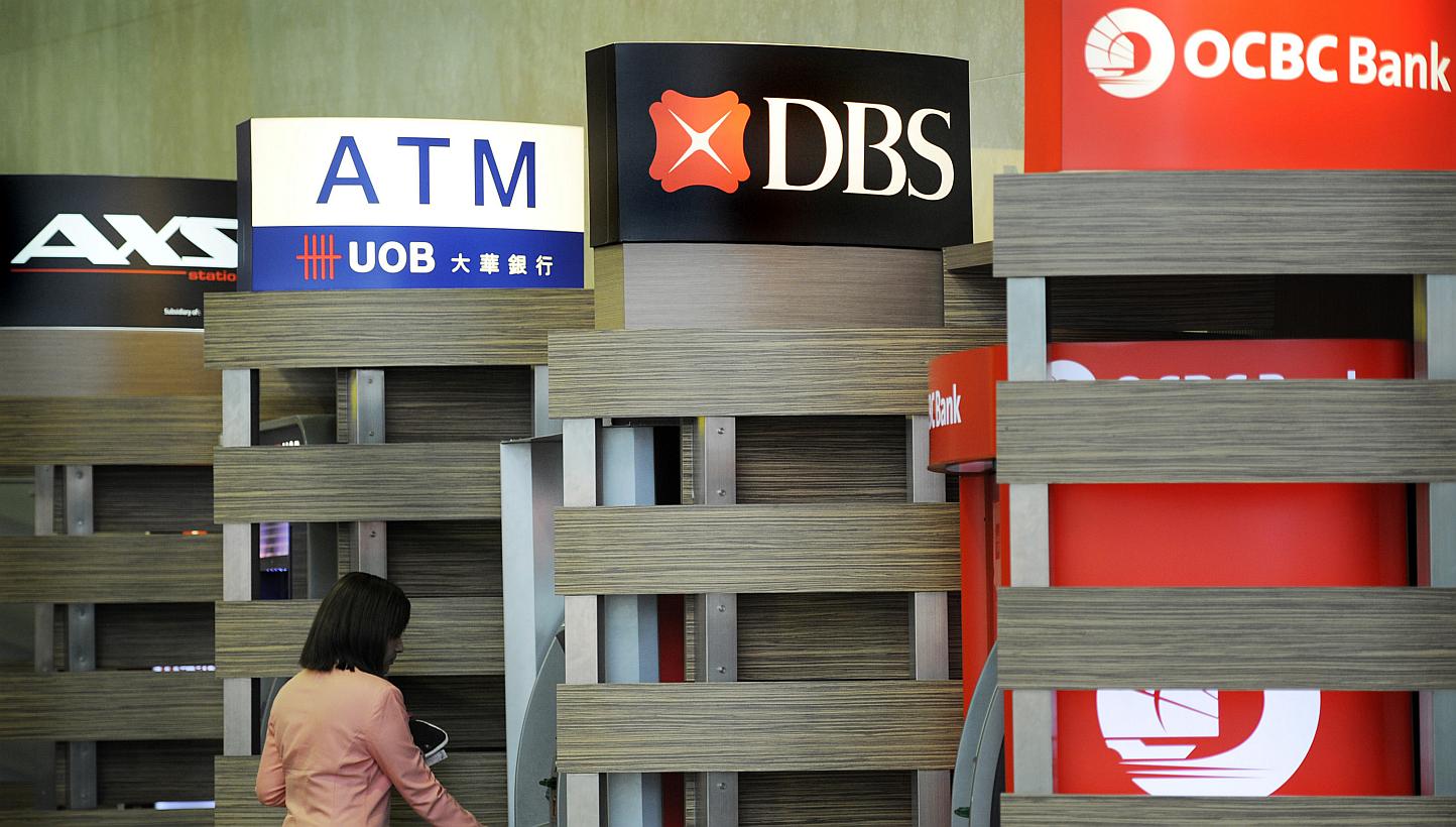 A customer using a DBS automated teller machine (ATM), standing between the ATMs of UOB and OCBC, at Changi Airport. Credit rating agency Moody's Investors Service says a number of differences among Singapore's three biggest lenders could lead to the