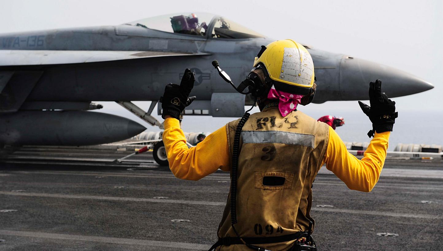 An aircraft handler directs an F/A-18E Super Hornet on the flight deck on board the aircraft carrier USS Theodore Roosevelt (CVN 71) on May 3, 2015. The United States and its allies have conducted 16 air strikes since early on Tuesday, May 12, target