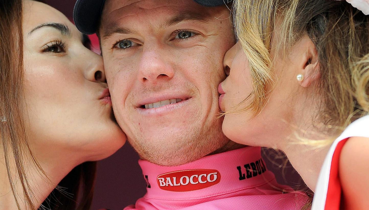 Australian rider Simon Clarke (centre) of the Orica-GreenEdge team is kissed by two hostesses on the podium after taking the overall leader's pink jersey following the fourth stage of the 98th Giro d'Italia cycling tour over 150km from Chiavari to La