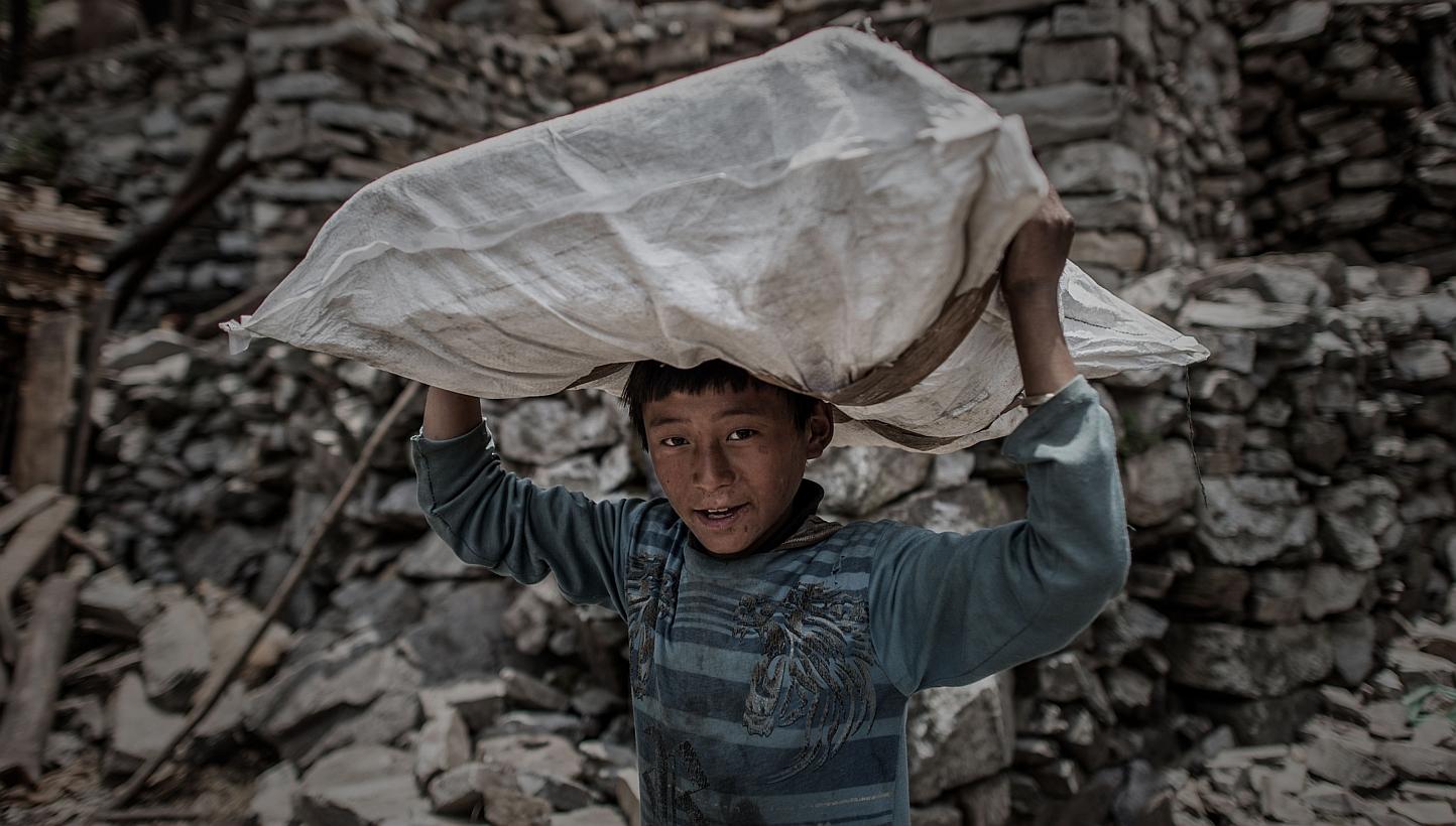 A Nepalese arthquake survivor carries relief supplies delivered by a World Food Programme (WFP) helicopter in the remote Kerauja village in Gorkha district. -- PHOTO: AFP