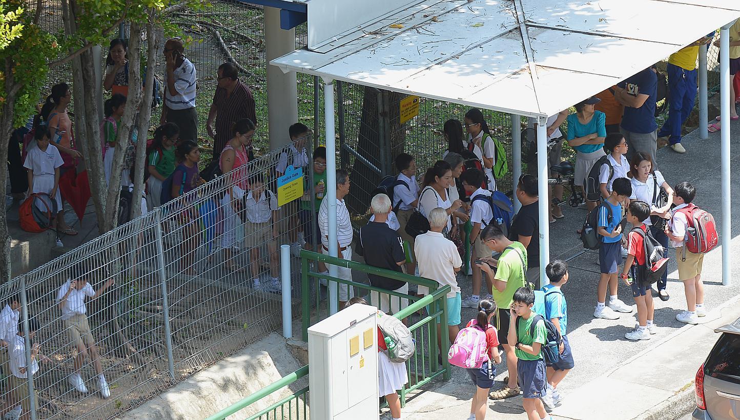 An entrance to Pei Chun Public School bustling with activity around noon as morning-session pupils leave and afternoon-session pupils arrive.