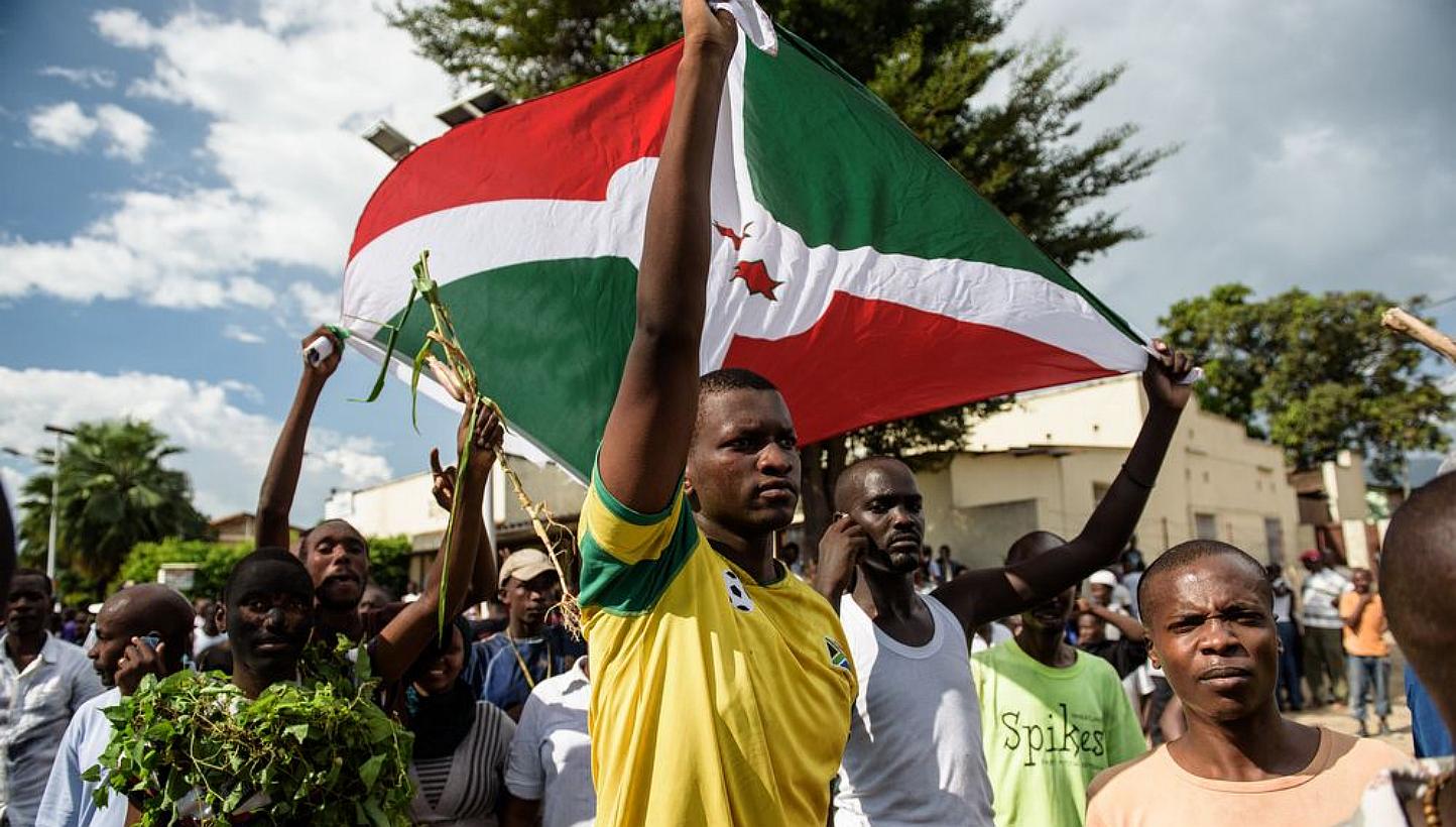 Men hold a Burundi's flag as people take to the streets to celebrate, waving branches, beeping car horns and parading through Bujumbura on May 13, 2015 following the radio announcement by Major General Godefroid Niyombare that President Nkurunziza wa