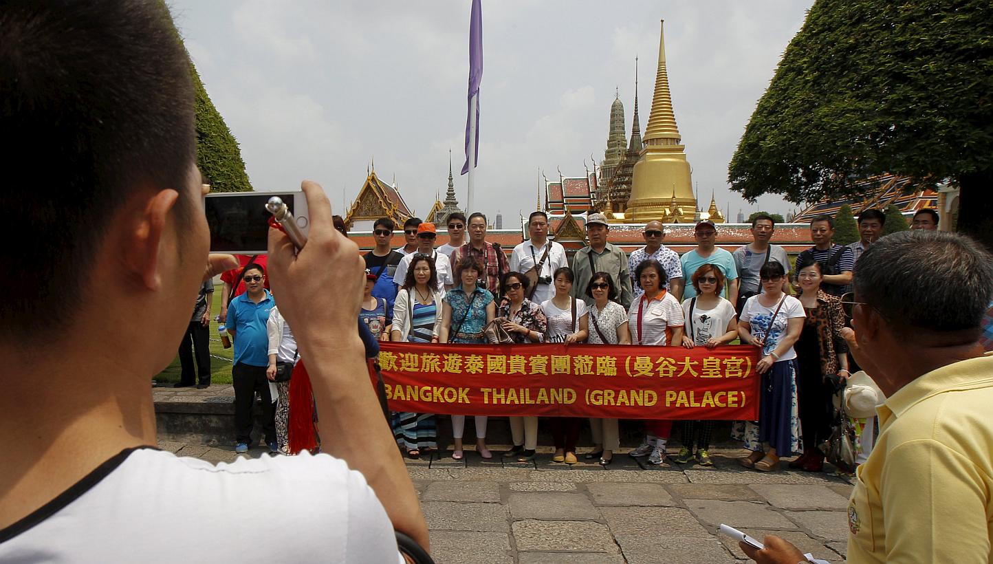 Chinese tourists pose for photos as they visit Wat Phra Kaeo (Emerald Buddha Temple) in Bangkok on March 23, 2015. A Chinese company is sending more than 12,000 people on a holiday to Thailand, tourism officials said Thursday, with one resort ho