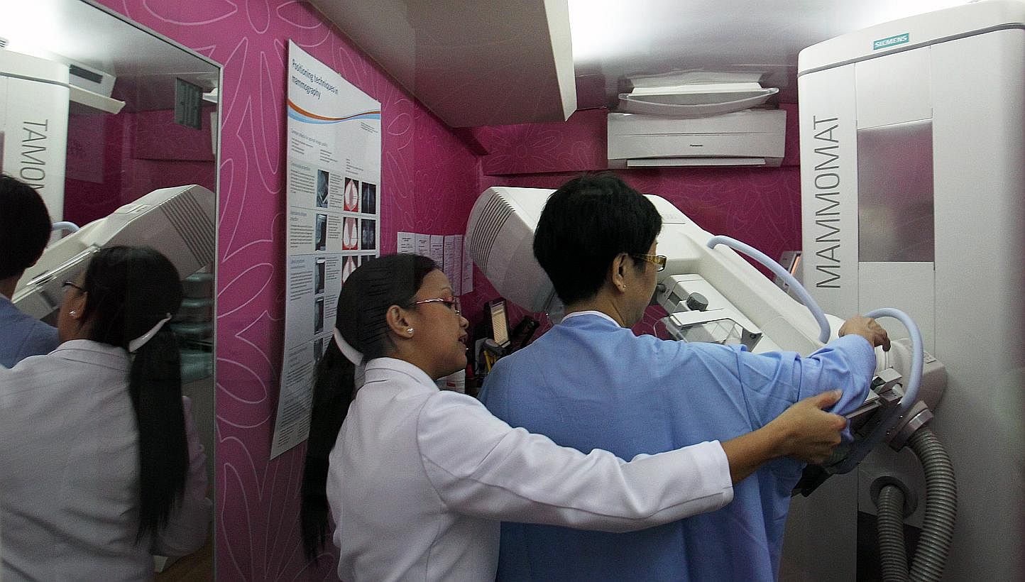 A National Healthcare Group radiographer (in white) preparing a woman for a mammogram. -- PHOTO: ST FILE