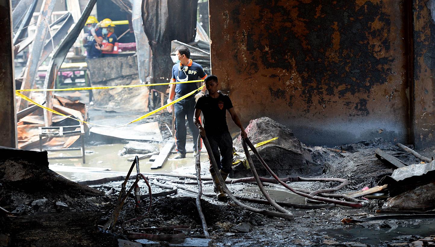 Fire investigators looking for evidence amongst the ruins of a footwear factory in suburban Manila on May 14, 2015, a day after the it was gutted by fire. -- PHOTO: AFP