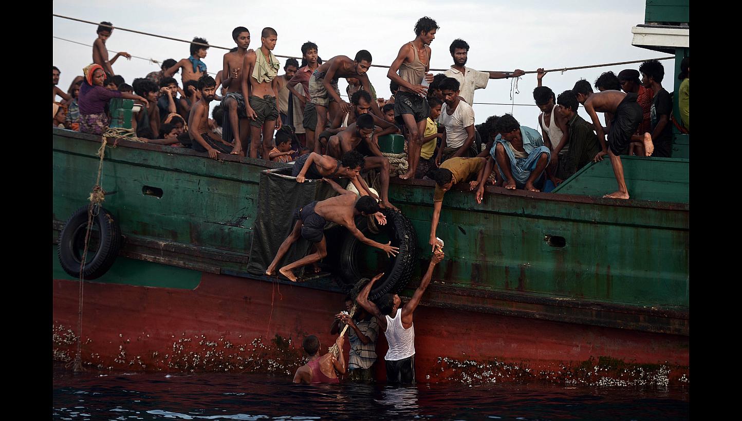 Rohingya migrants passing food supplies dropped by a Thai army helicopter to others aboard a boat off the southern island of Koh Lipe yesterday. The boat was found drifting in Thai waters, with passengers saying several people had died over the last 