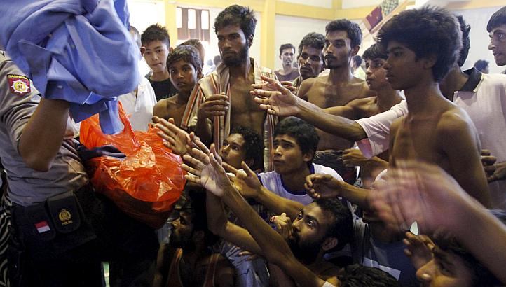 An Indonesia policeman distributes used clothes to migrants believed to be Rohingya inside a shelter in Lhoksukon, in Indonesia's Aceh province on May 11, 2015. -- PHOTO: REUTERS