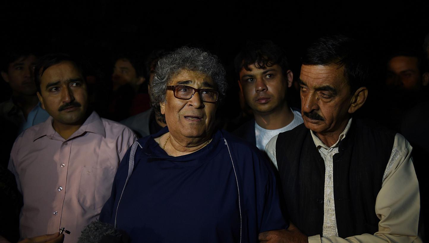 Afghan classical singer Altaf Hussain (centre) who was due to host a concert walks after being rescued by security forces at the Park Place guesthouse in Kabul on May 14, 2015.&nbsp;Fourteen people, most of them foreigners, were killed in a Taleban a