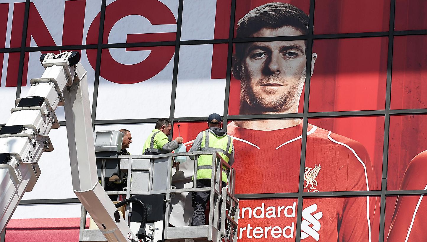 Workers pasting a poster over Liverpool's English midfielder Steven Gerrard as they replace sections of a mural outside The Kop stand at Anfield, Liverpool, north-west England on May 13, 2015. -- PHOTO: AFP
