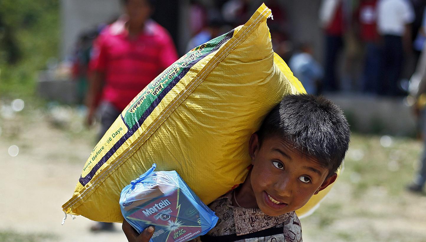 A Nepalese earthquake survivor carries a sack of rice during a food distribution in Jaharsingh Pauwa, Nepal on May 16, 2015. -- PHOTO: EPA