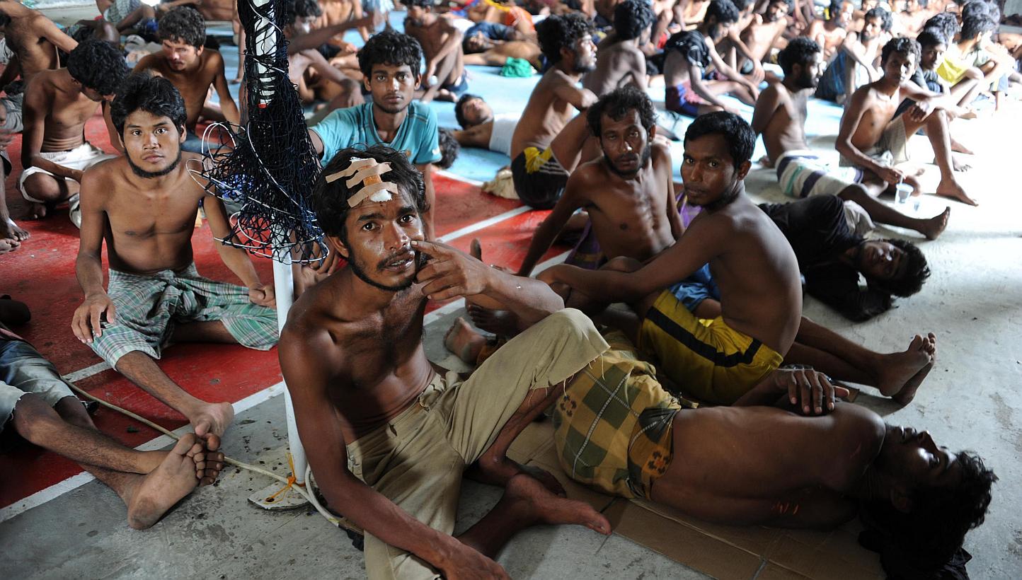 A group of rescued migrants, mostly Rohingya from Myanmar and Bangladesh, sit upon their arrival at the new confinement area in the fishing town of Kuala Langsa in Aceh province on May 15, 2015. -- PHOTO: AFP