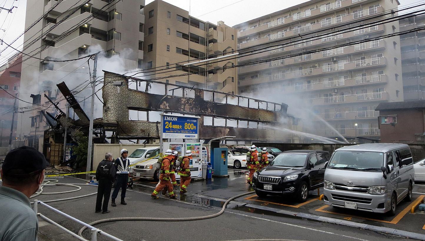 Firefighters spray water on a day-laborer's lodging house in Kawasaki, Kanagawa prefecture in suburban Tokyo on May 17, 2015. At least four people were killed in a fire early Sunday at two adjacent hostels in Kawasaki, south-west of Tokyo, while 19 o