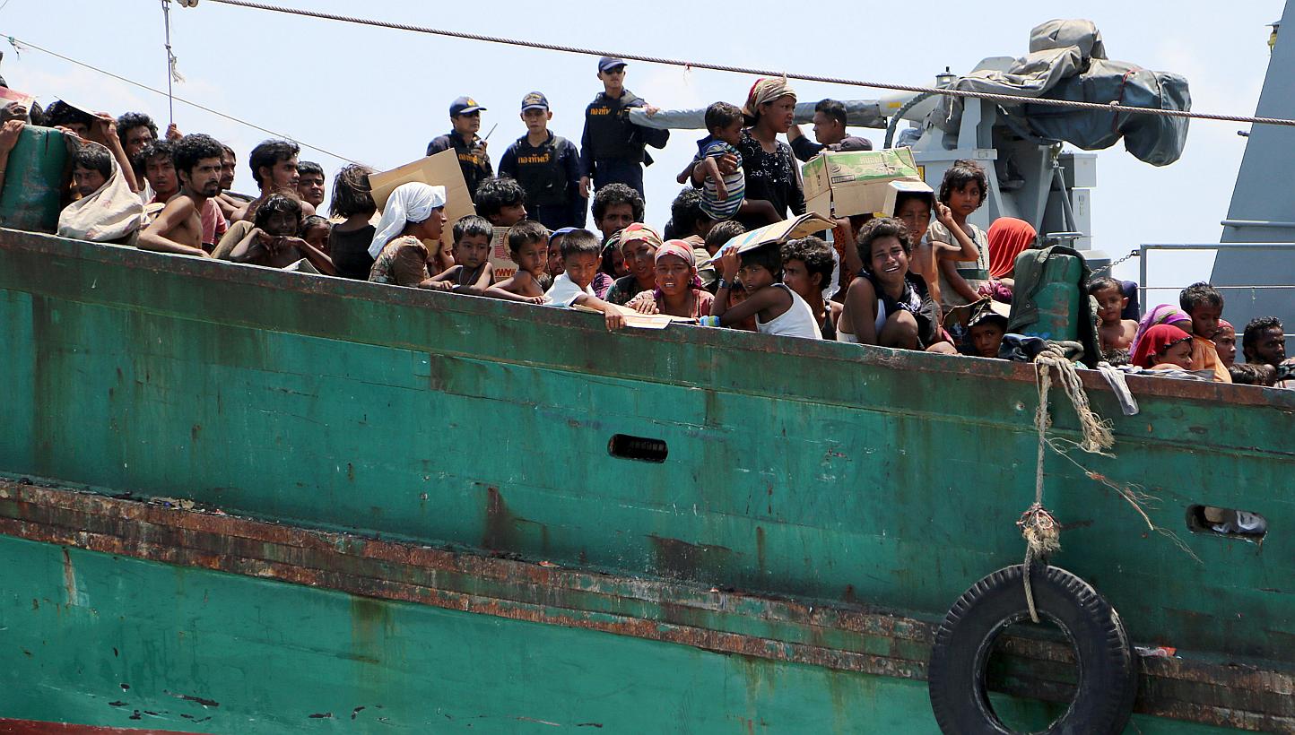 Navy officers look at migrants on their boat being towed away from Thailand by a Thai navy vessel, in waters near Koh Lipe island on May 16, 2015. -- PHOTO: REUTERS
