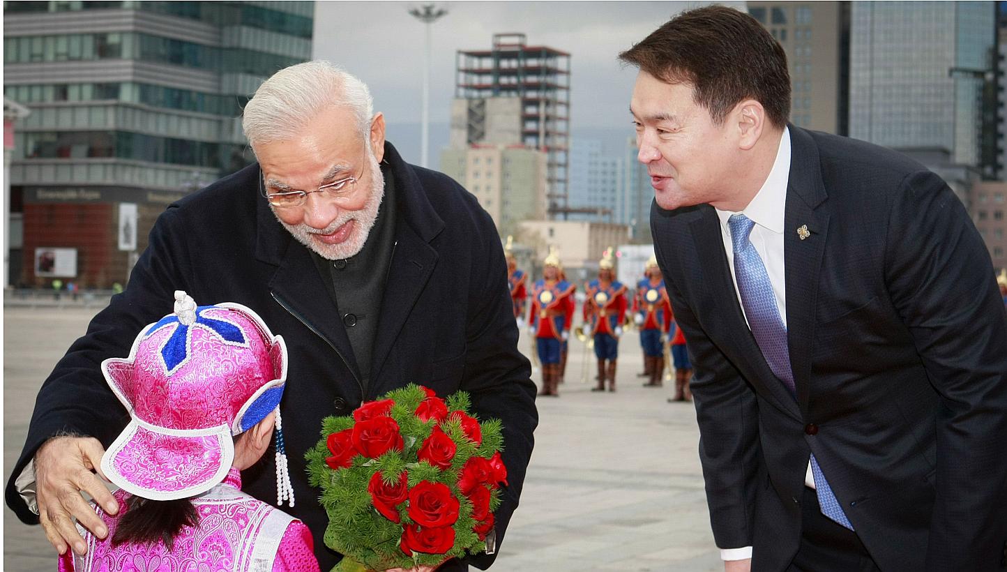 Mongolian Prime Minister Chimed Saikhanbileg (right) looks on as India's Prime Minister Narendra Modi receives a bouquet of flowers from a Mongolian child during a welcoming ceremony at the Chinggis Square in Ulan Bator on May 17, 2015. Mr&nbsp;Modi 