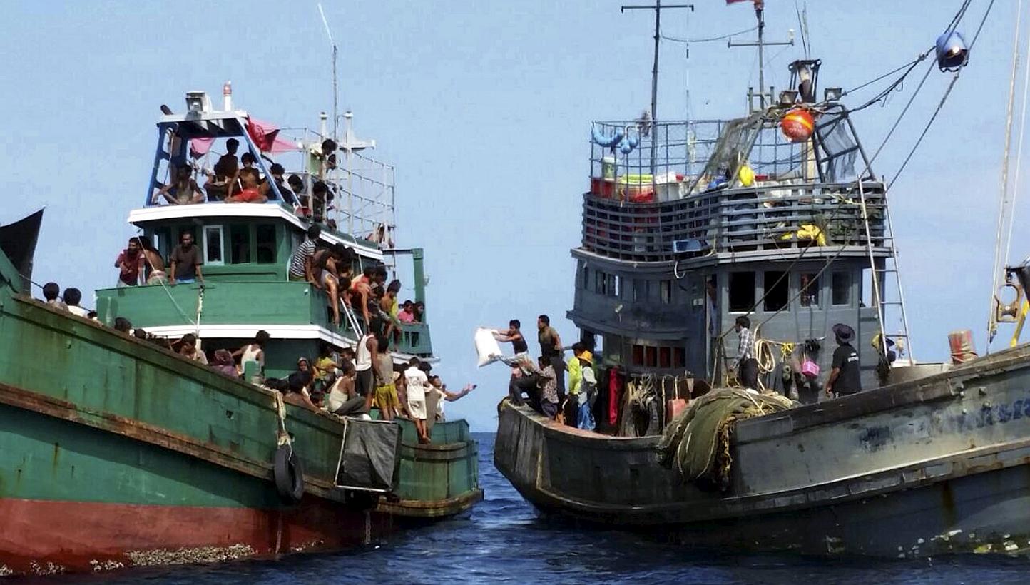 Thai fishermen (right) giving some supplies to migrants on a boat drifting 17km off the coast of the southern island of Koh Lipe, Thailand on May 14, 2015. -- PHOTO: REUTERS