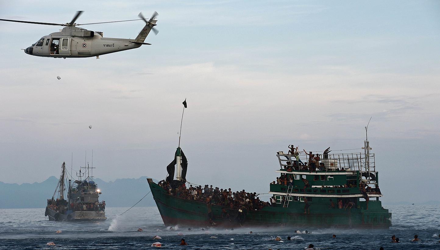 Rohingya migrants swimming to collect food supplies dropped by a Thai army helicopter after they jumped from a boat (right) drifting in Thai waters off the southern island of Koh Lipe in the Andaman sea on May 14, 2015.&nbsp; -- PHOTO: AFP