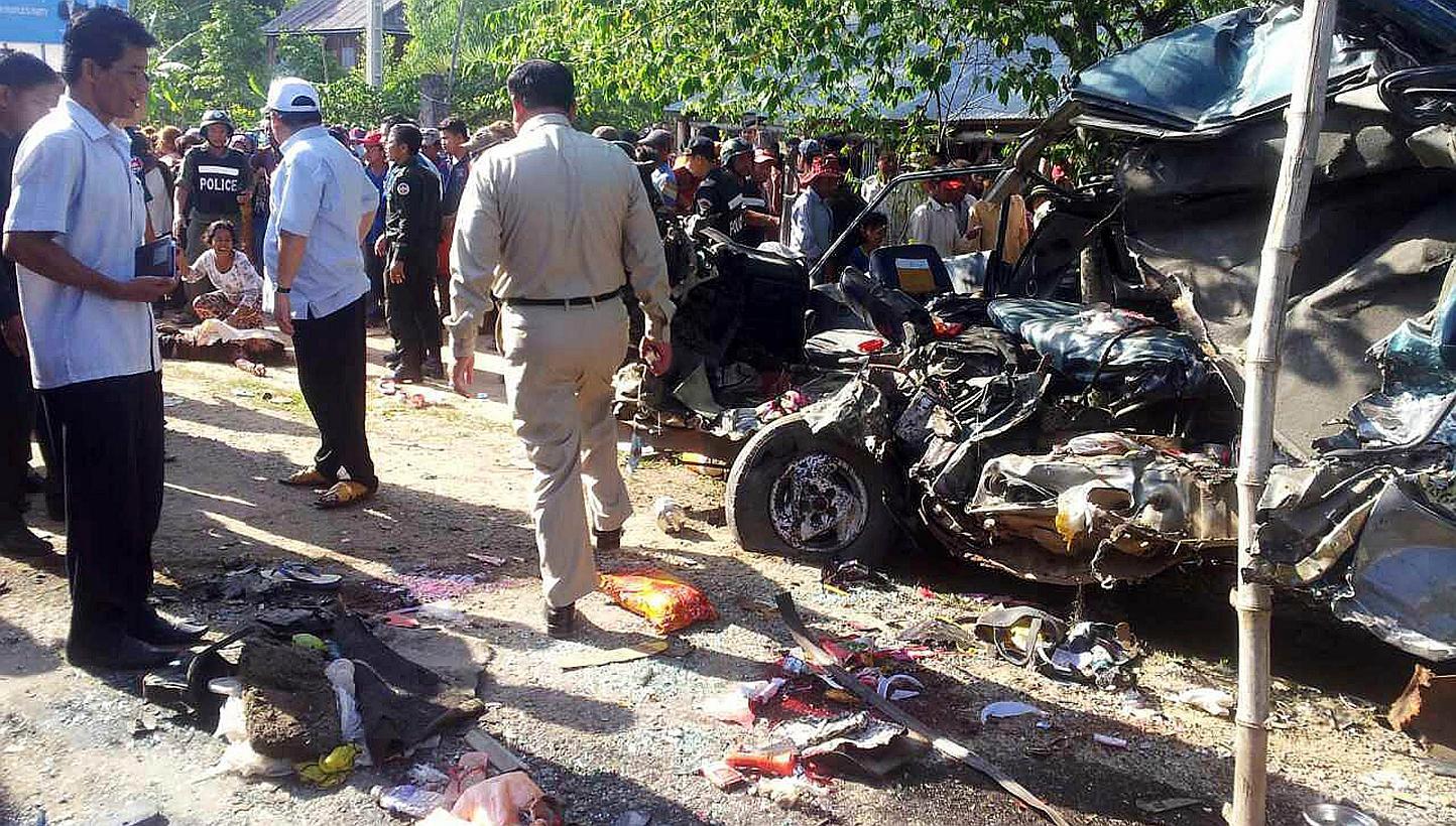 A Cambodian police officer (centre) examining damages of a van after an accident in Svay Rieng province on May 19, 2015. -- PHOTO: AFP