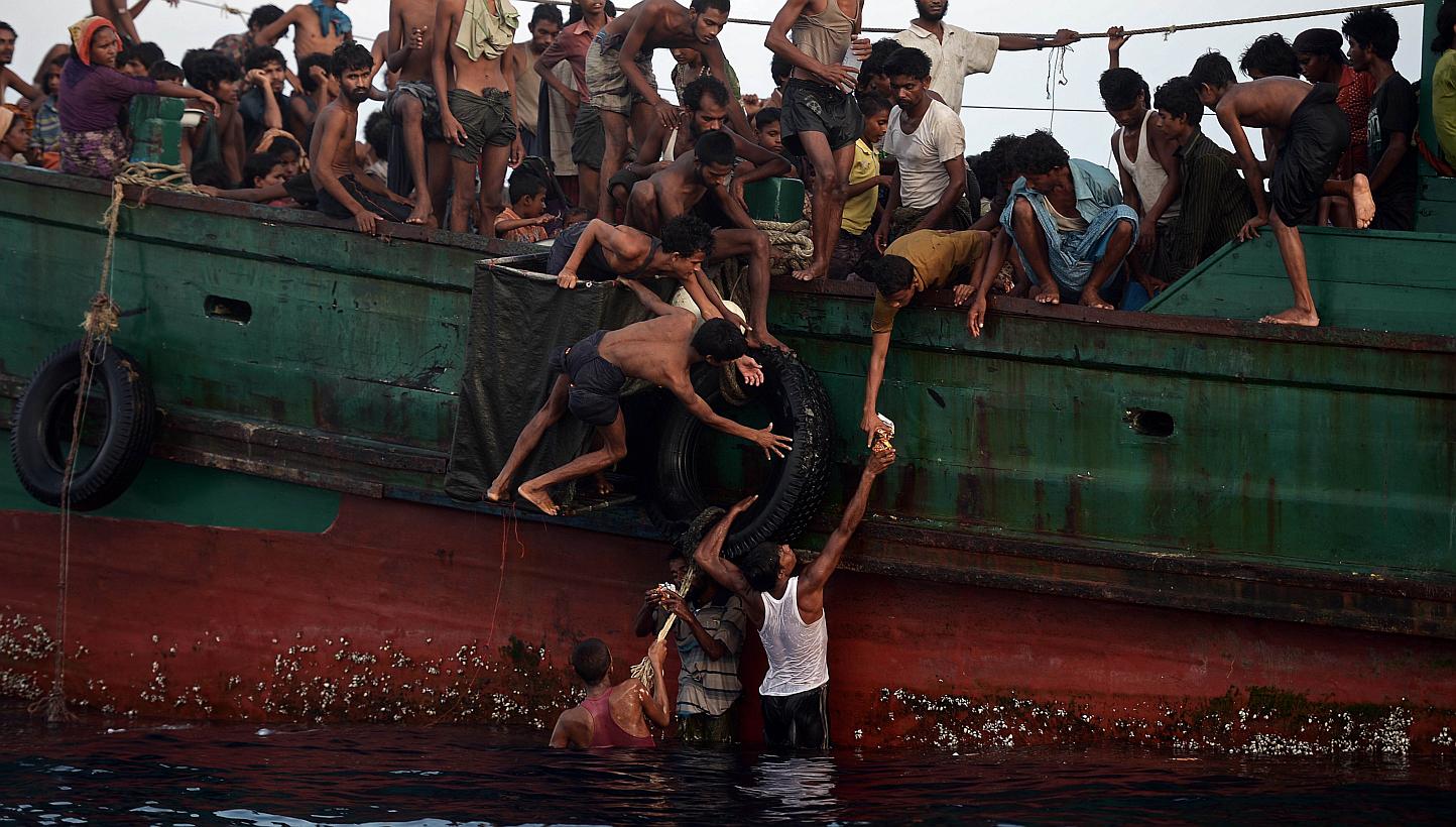 Rohingya migrants passing food supplies dropped by a Thai army helicopter to others aboard a boat drifting in Thai waters off the southern island of Koh Lipe in the Andaman sea on May 14, 2015. -- PHOTO: AFP