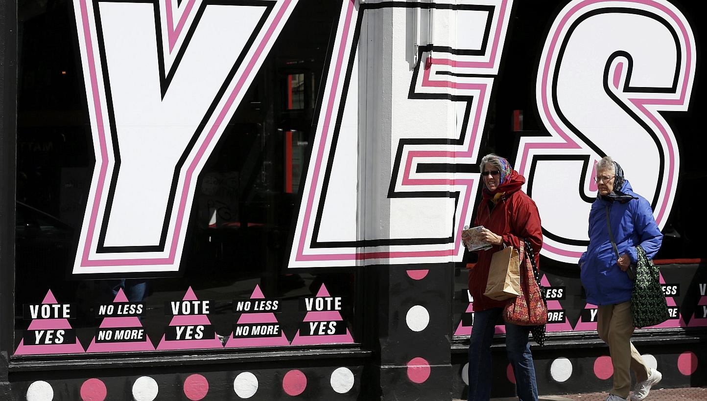 People walk past posters supporting the Yes vote, in the Caple Street area of Dublin in Ireland on Monday. Irish voters are set to back the introduction of gay marriage by a margin of as much as two-to-one and become the first country to approve the