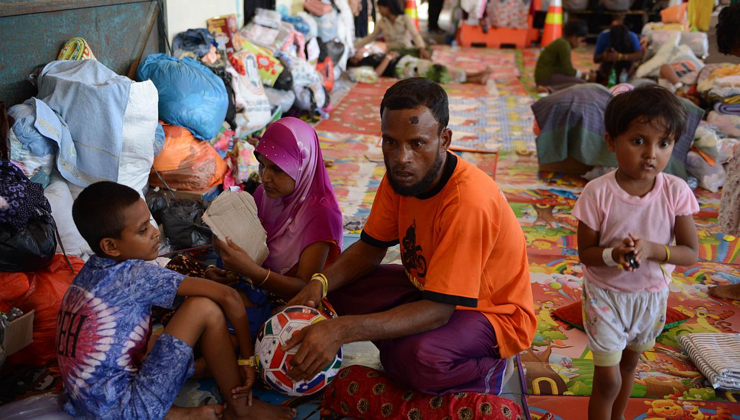 Rescued Rohingya migrant from Myanmar, Mohammad Amih (C), sits with other survivors at the port in Langsa in Aceh. A vicious fight among Rohingya and Bangladeshi migrants on board a foundering vessel off Indonesia left at least 100 dead, survivors sa