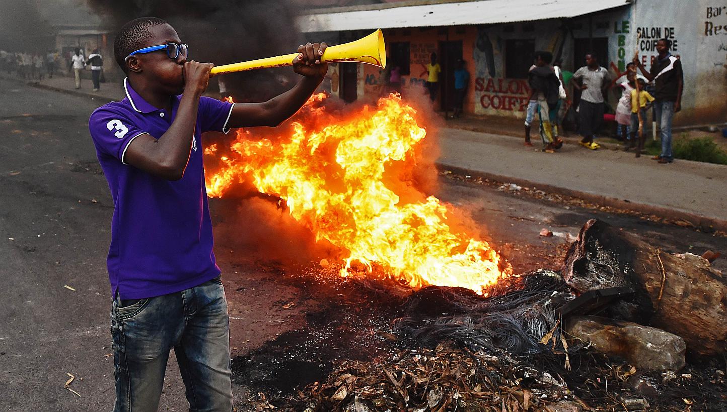Protestors opposed to the Burundian president Pierre Nkurunziza's third term in office gather by a burning barricade during a demonstration in the Cibitoke neighbourhood of Bujumbura on May 19, 2015. Burundian security forces fired shots and tear gas