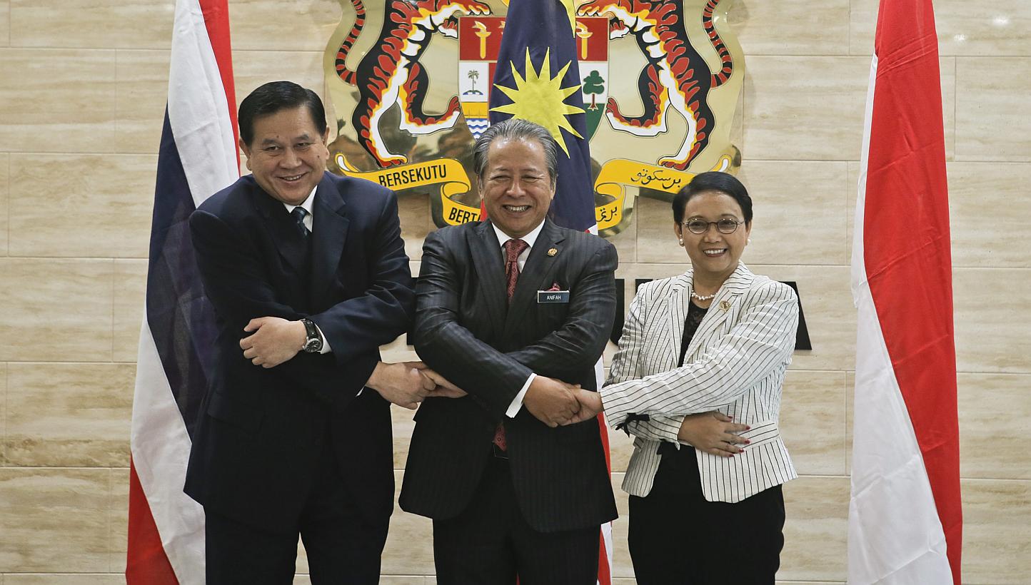 Ministers of Foreign Affairs from Thailand, Mr Tanasak Patimapragorn (left), Malaysia,&nbsp;Datuk Seri Anifah Aman (centre), and Indonesia, Ms Retno Marsudi (right) holding hands during a meeting on human trafficking and people smuggling in Putrajaya