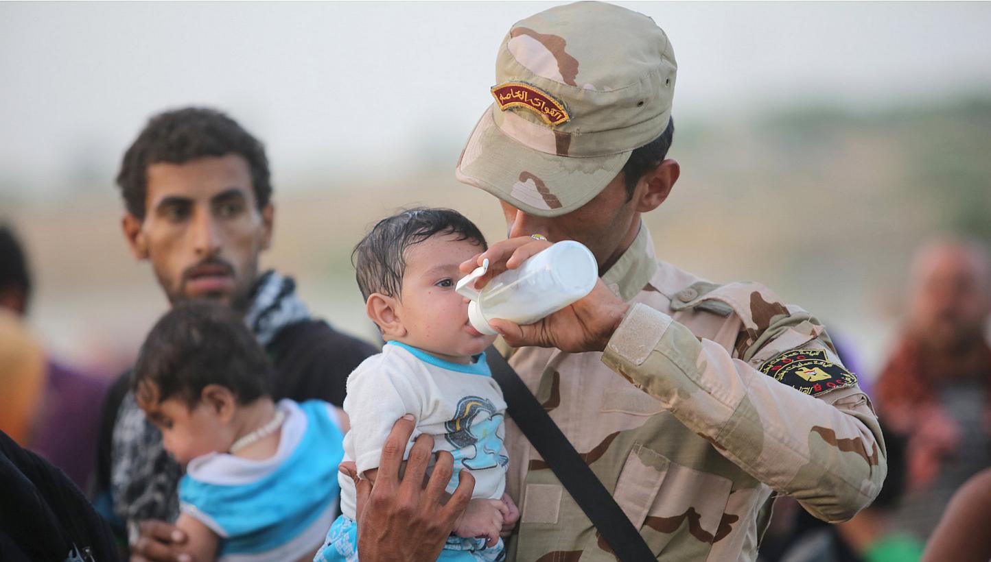 An Iraqi soldier carrying a displaced child from Ramadi on the outskirts of Baghdad on May 19, 2015. US President Barack Obama weighed faster training and arms supplies for Iraqi tribes on Tuesday, while eyeing a rapid counteroffensive to retake Rama
