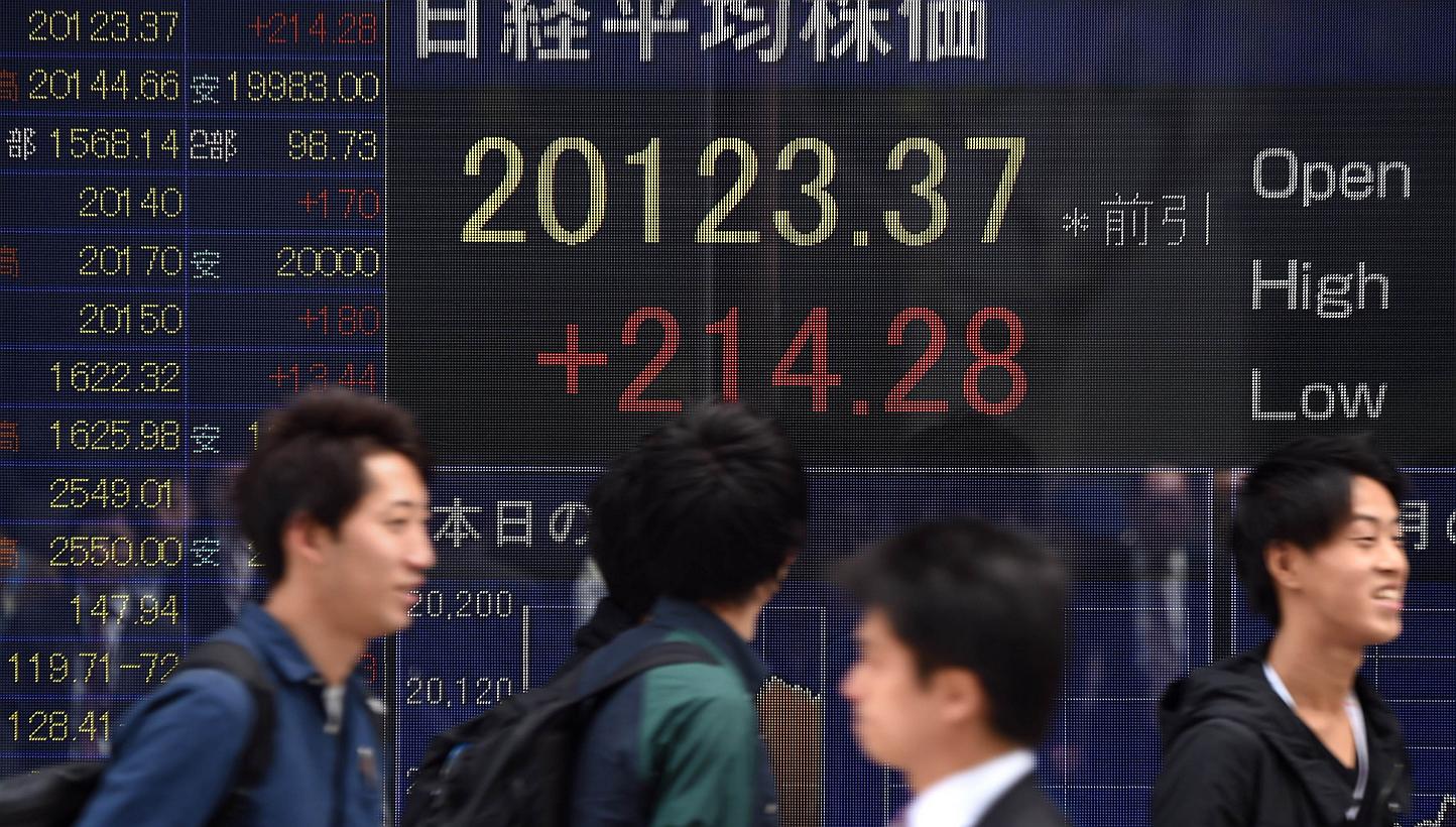 People walking past an electric quotation board flashing the numbers of the Nikkei key index at the Tokyo Stock Exchange (TSE) in front of a securities company in Tokyo. -- PHOTO: AFP