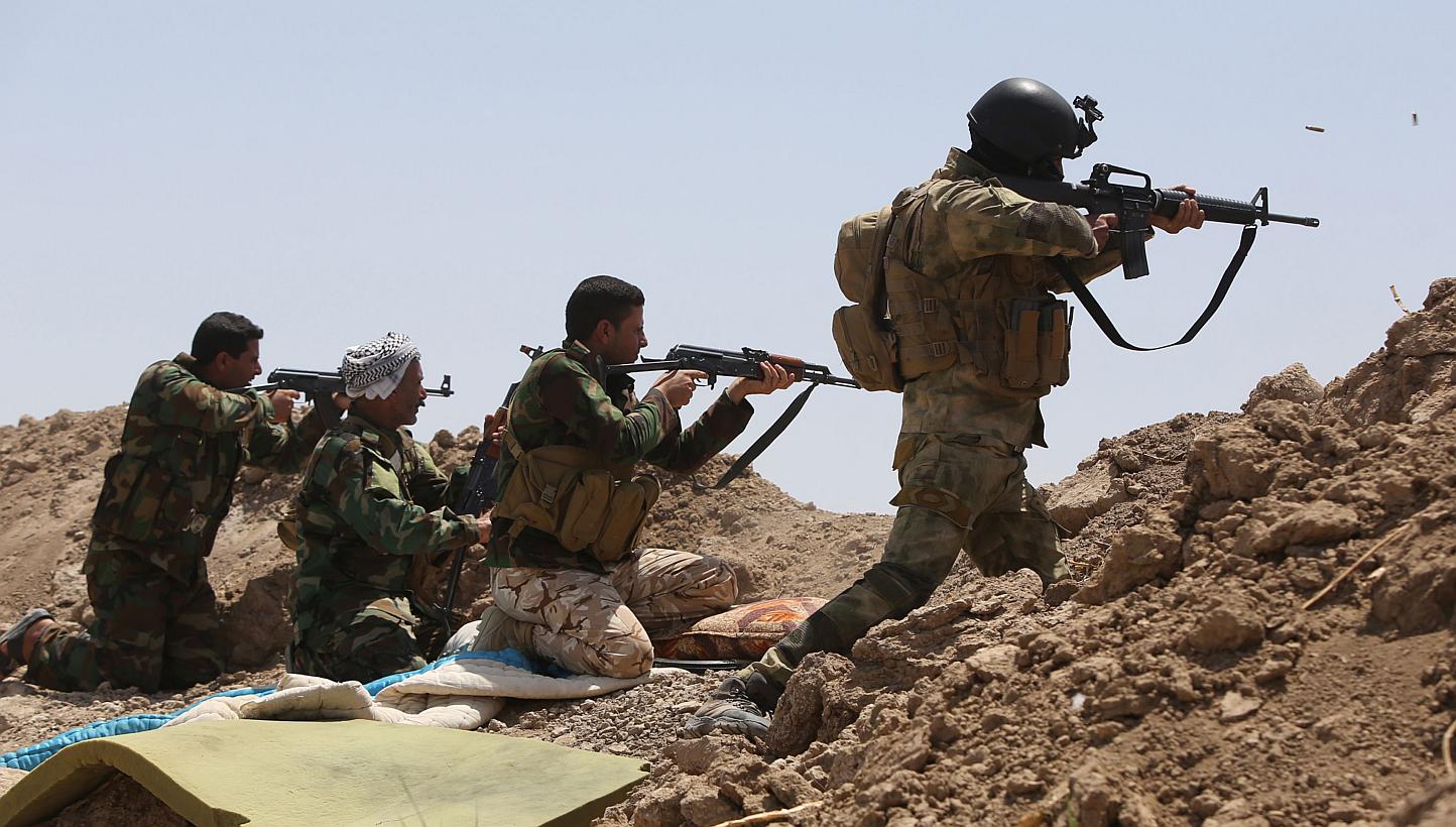 Iraqi soldiers and Shi'ite fighters from the popular committees firing towards Islamic State in Iraq and Syria (ISIS) positions in the Garma district of Anbar province west of the Iraqi capital Baghdad, on May 19, 2015.&nbsp;Iraqi forces thwarted an 