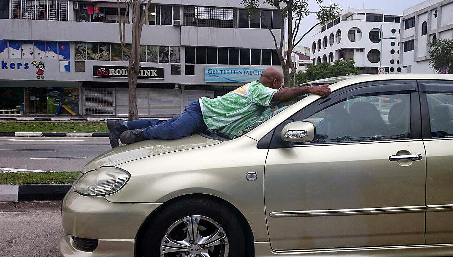 Mr Haresh Govindaraju clinging on to the windscreen of the car driven by Murali Krishnan Naidu, who was fined $2,000 and banned from the road for nine months. -- PHOTO: LIANHE ZAOBAO