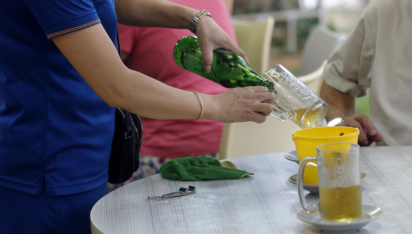 A beer promoter serving drinks at a coffeeshop in Toa Payoh Central. -- ST PHOTO: CHEW SENG KIM