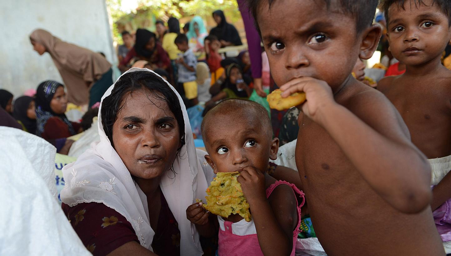 Rescued Rohingya women and children are provided with food by Indonesian residents in the compound of a mosque in Julok district, Aceh province, on May 20, 2015, after they were rescued by Indonesian fishermen off the waters of the eastern coast of A
