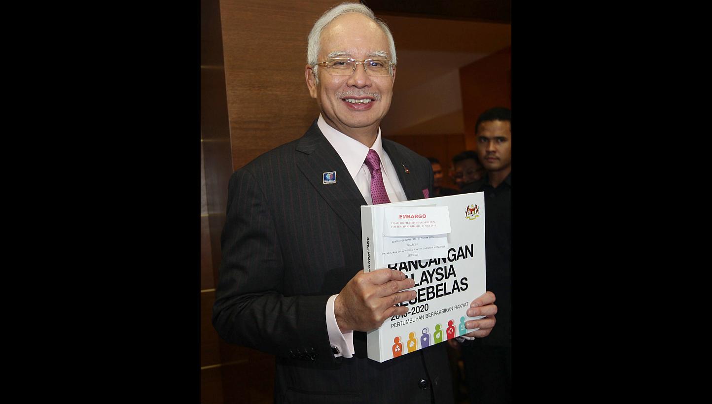 Mr Najib Razak with the 11th Malaysia Plan after tabling it in Parliament. The aim is "to break the country out of 'business as usual' practices and set Malaysia on an accelerated growth trajectory", he says.