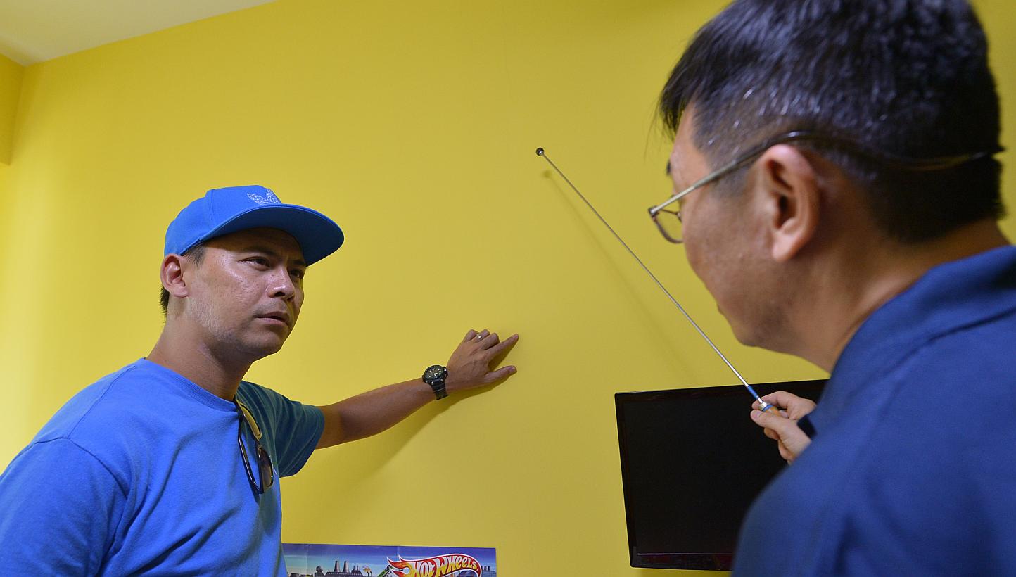 Security officer Mohamad Rizan Mazlan pointing out cracks on a wall in his Waterway Banks flat to a professional home inspector. Other residents in the estate say they have spotted cracks on their walls too.