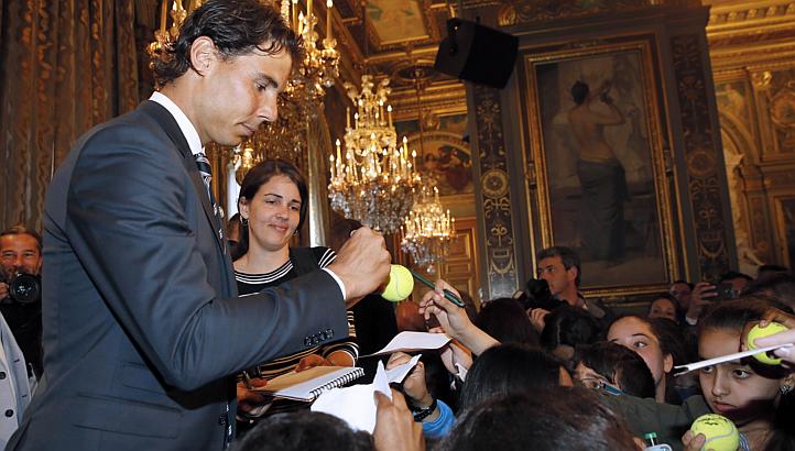 Rafael Nadal (left) autographs tennis balls for supporters after receiving the Vermeil Medal of the City of Paris on May 21, 2015 in Paris. -- PHOTO: AFP 