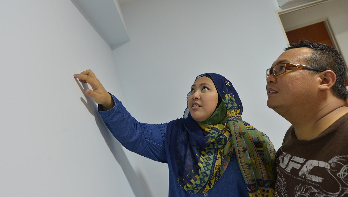 Ms Mazuwina Mohamad, 34, and her husband, Mr Jumani Samat, 35, pointing out cracks in the wall of their Punggol flat. -- ST PHOTO: ALPHONSUS CHERN&nbsp;