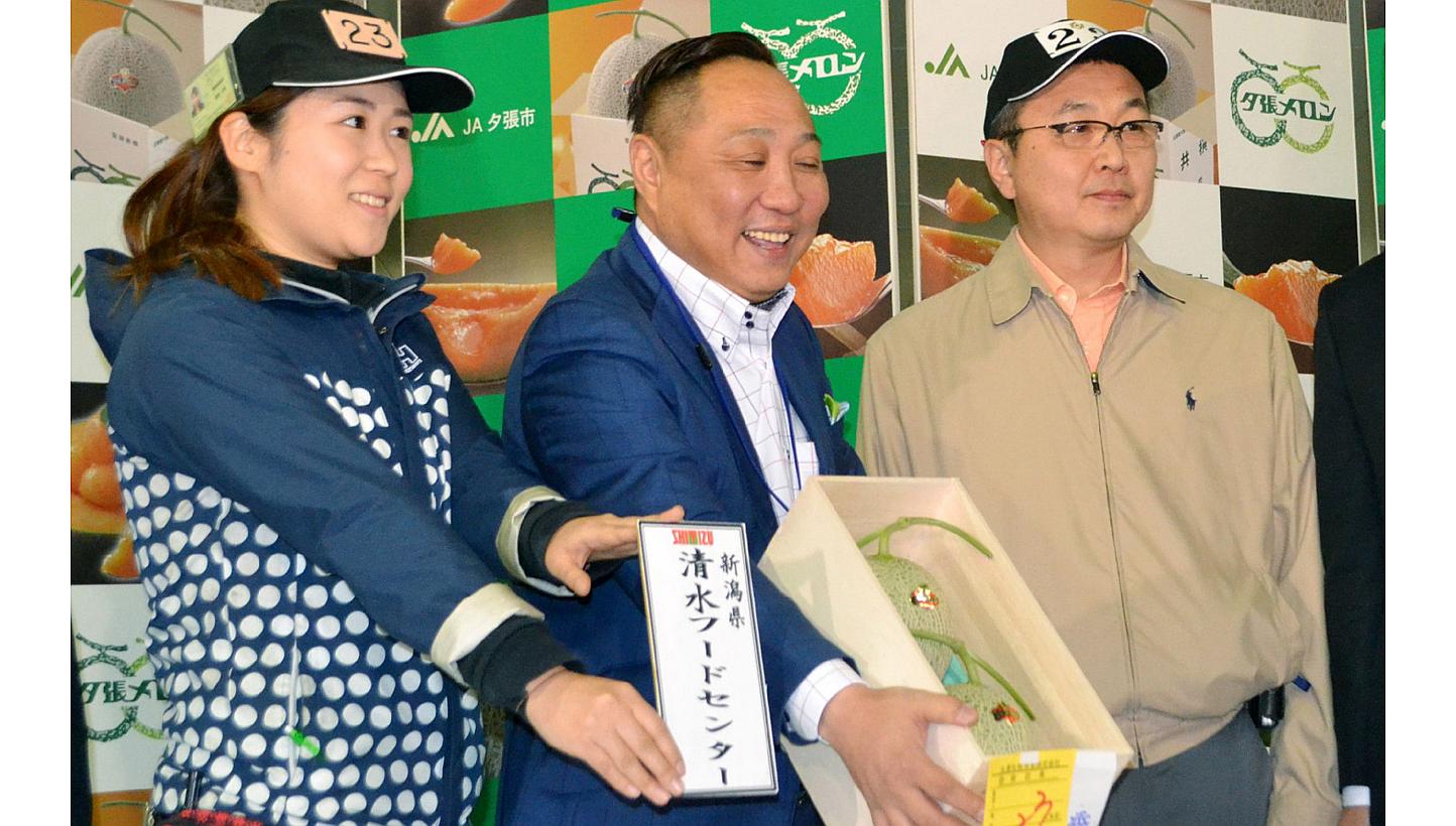 The successful bidder (centre) showing the pair of Yubari melons after this year's first auction at the Sapporo Central Wholesale Market in Sapporo on May 22, 2015. -- PHOTO: AFP 