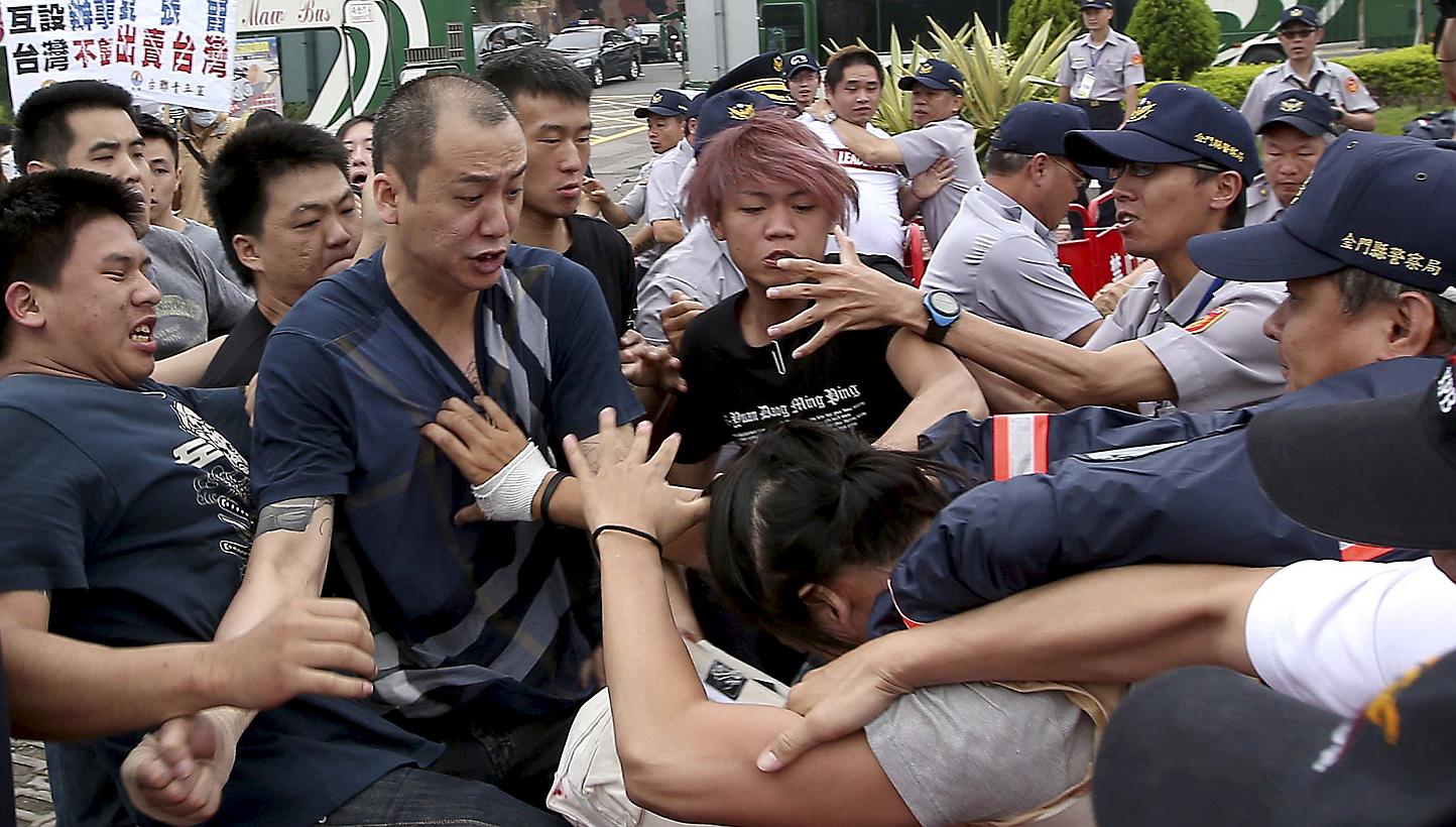 Pro-China activists (left in black shirts) fight with a pro-Taiwan activist (right in yellow vest) as police officers attempt to stop them in Kinmen, Taiwan's offshore island, on May 23, 2015. -- PHOTO: REUTERS