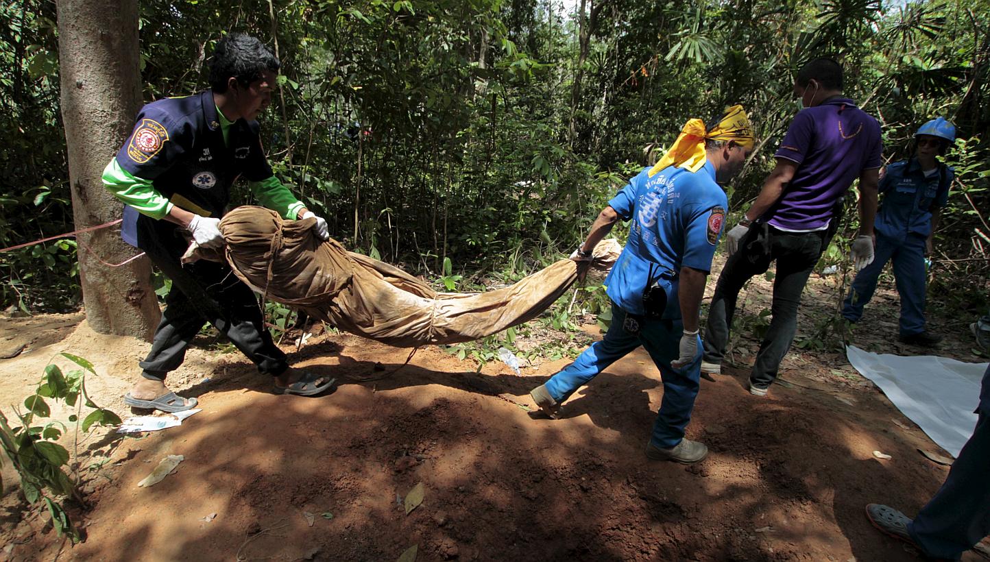 Rescue workers carry a body bag with remains retrieved from a mass grave at a rubber plantation near a mountain in Thailand's southern Songkhla province on May 6, 2015. Malaysian Prime Minister Najib Razak said on Monday that Malaysia will find those
